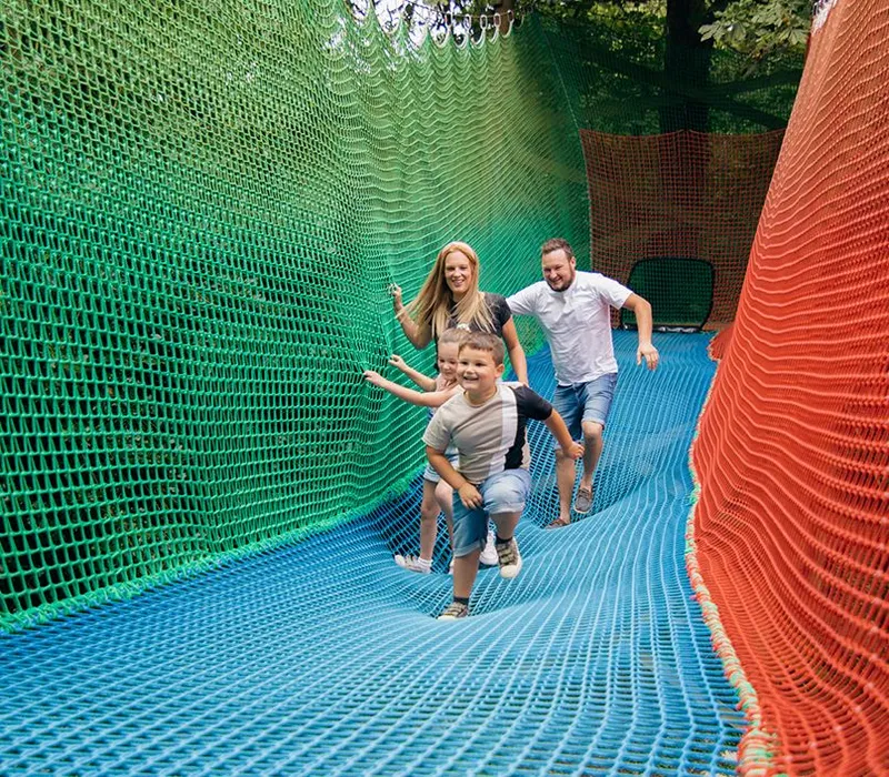 Family running through a colourful net tunnel adventure at Robin Hill