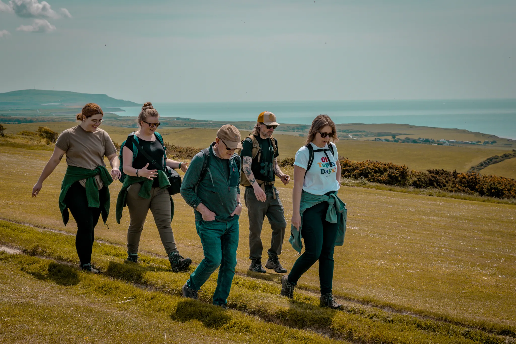 Group of walkers on the Tapnell Farm Wildlife Trail with rolling countryside and sea views in the background