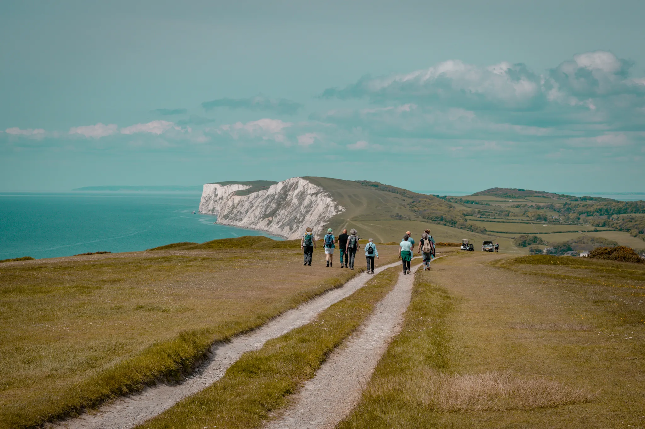 Group of walkers on a coastal path overlooking white cliffs and the sea during the Tapnell Wildlife Walk