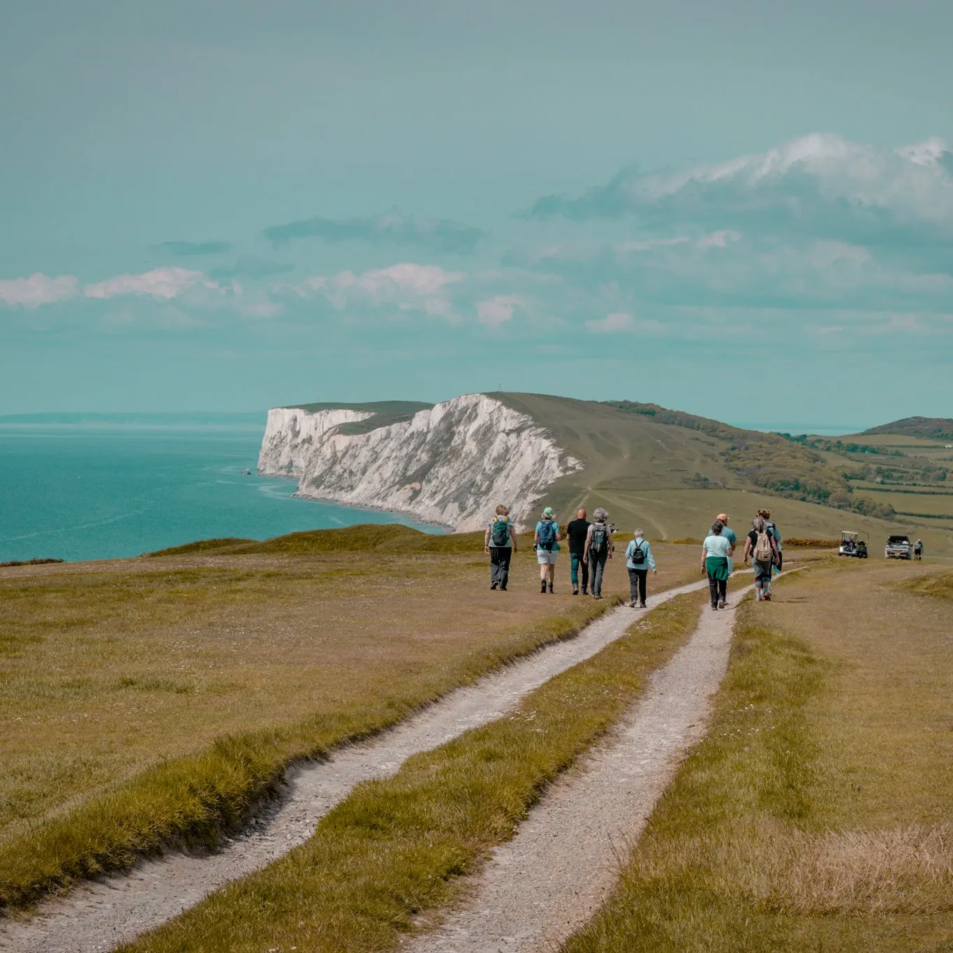 Group of walkers on a coastal path overlooking white cliffs and the sea during the Tapnell Wildlife Walk