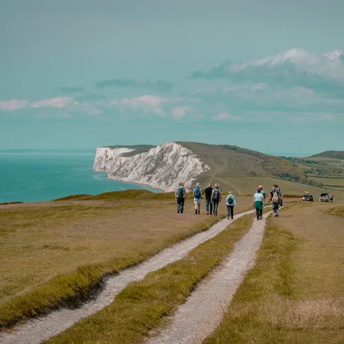 Group of walkers on a coastal path overlooking white cliffs and the sea during the Tapnell Wildlife Walk