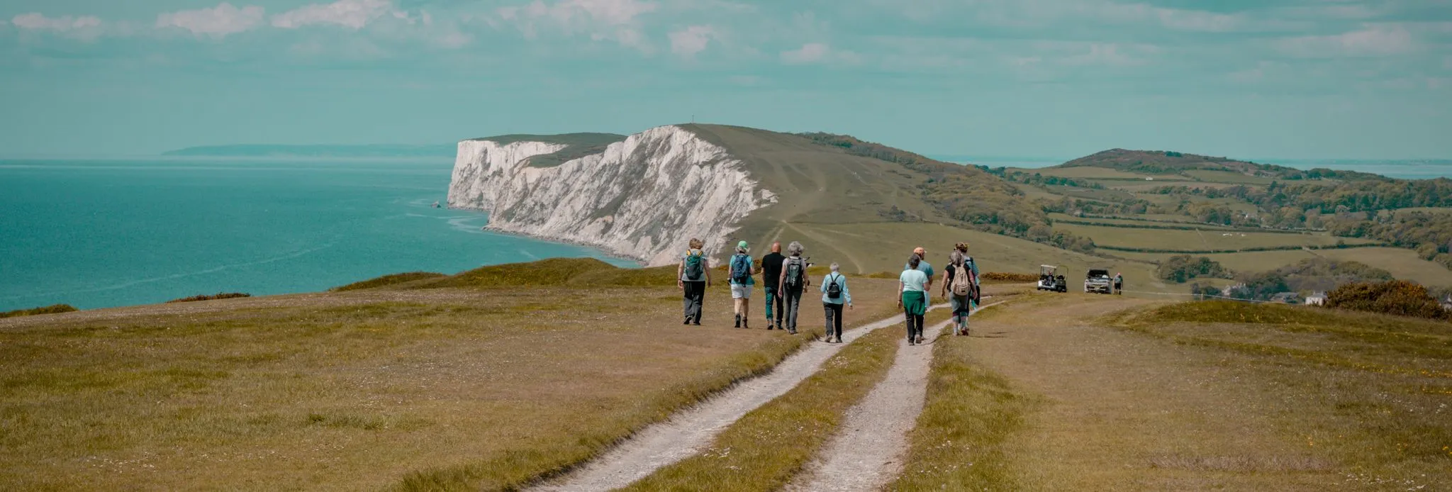 Group of walkers on a coastal path overlooking white cliffs and the sea during the Tapnell Wildlife Walk
