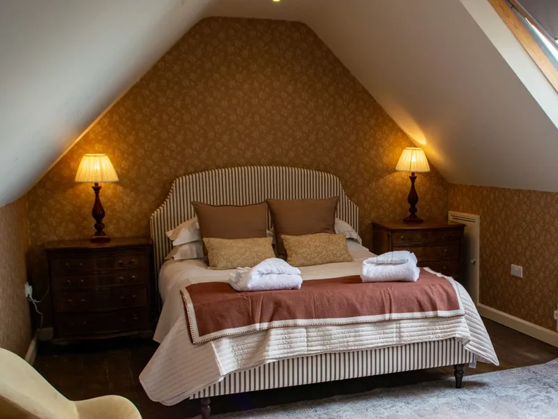 Cosy attic bedroom at Tapnell Manor Tennyson Room with a double bed, bedside lamps and a large skylight.
