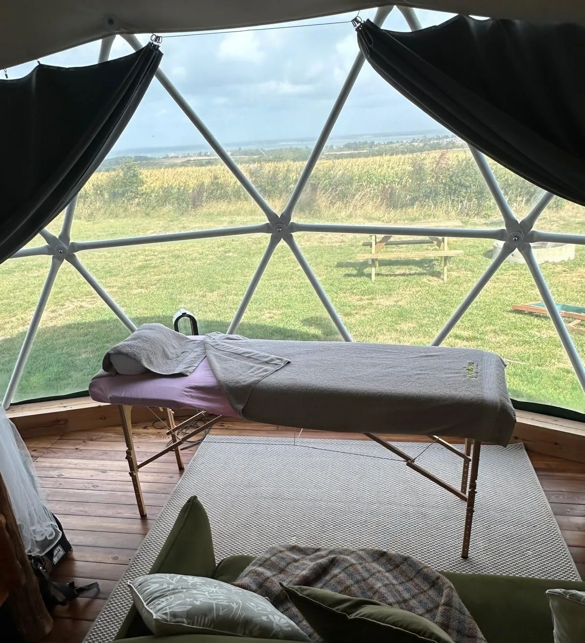 Massage table inside a geodesic dome with countryside views through large windows