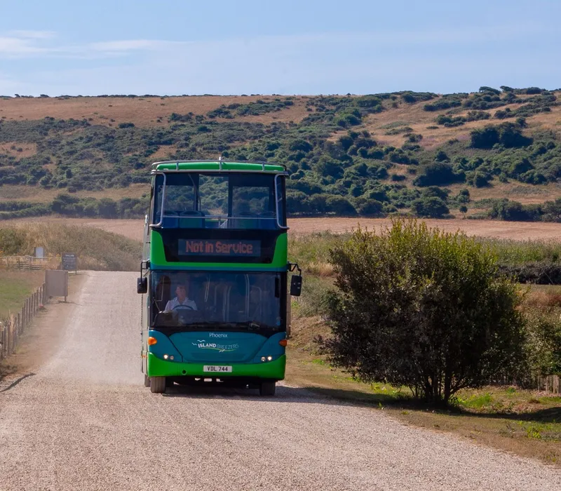 Green double-decker Island Breezers bus travelling along a country road near Tapnell Farm in summer