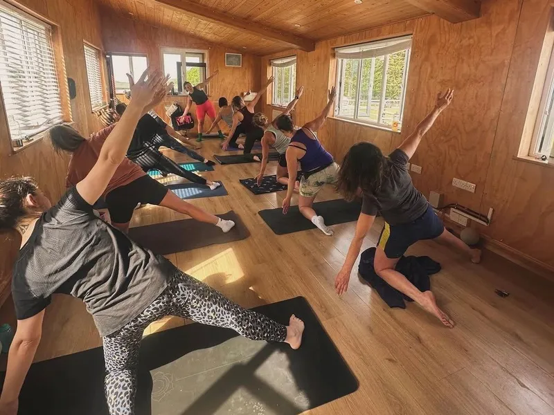 Group barre class taking place in a bright wooden studio at Tapnell, with participants stretching on mats.