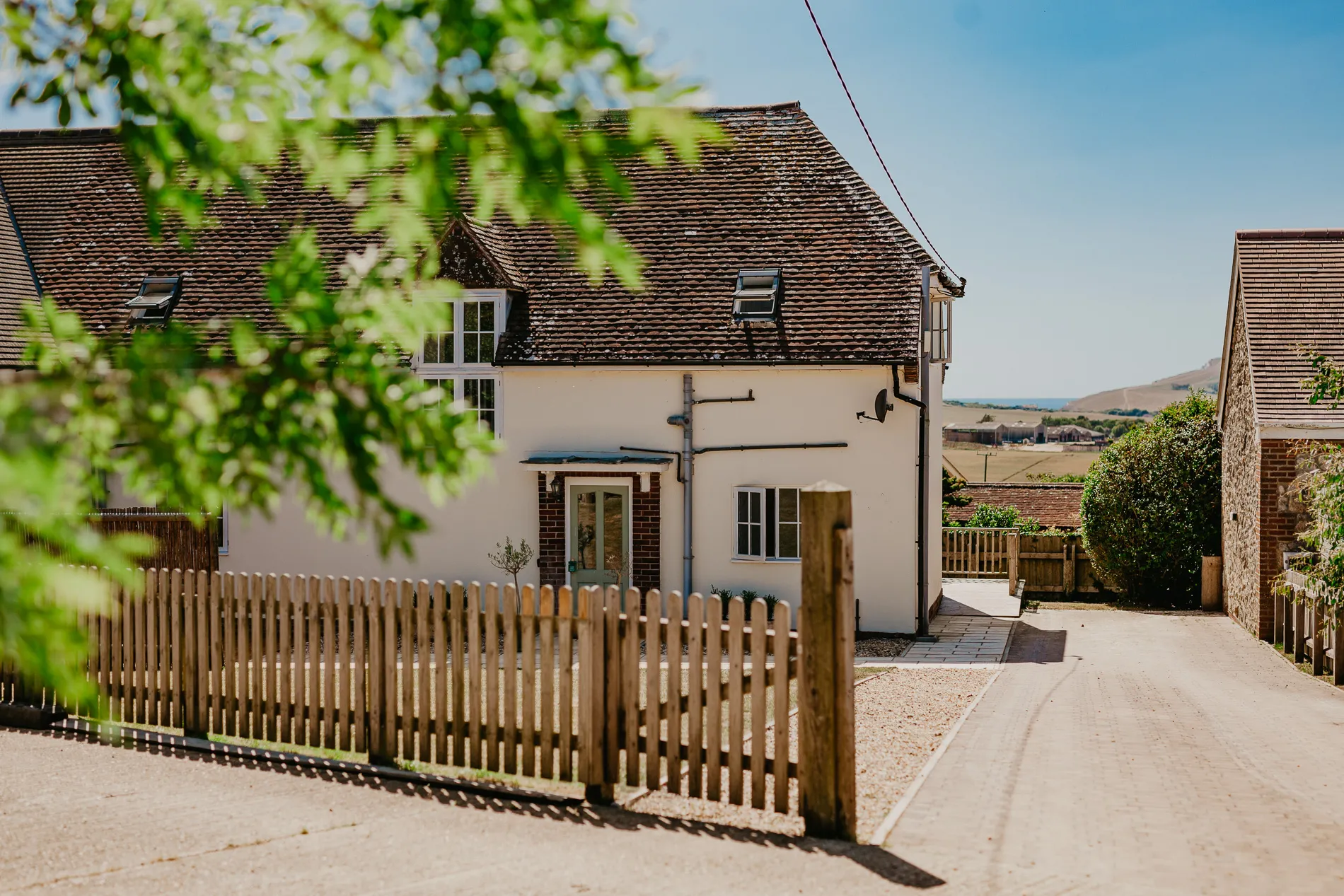 Exterior of Tapnell Farm Dairyman's Cottage with picket fence and countryside view