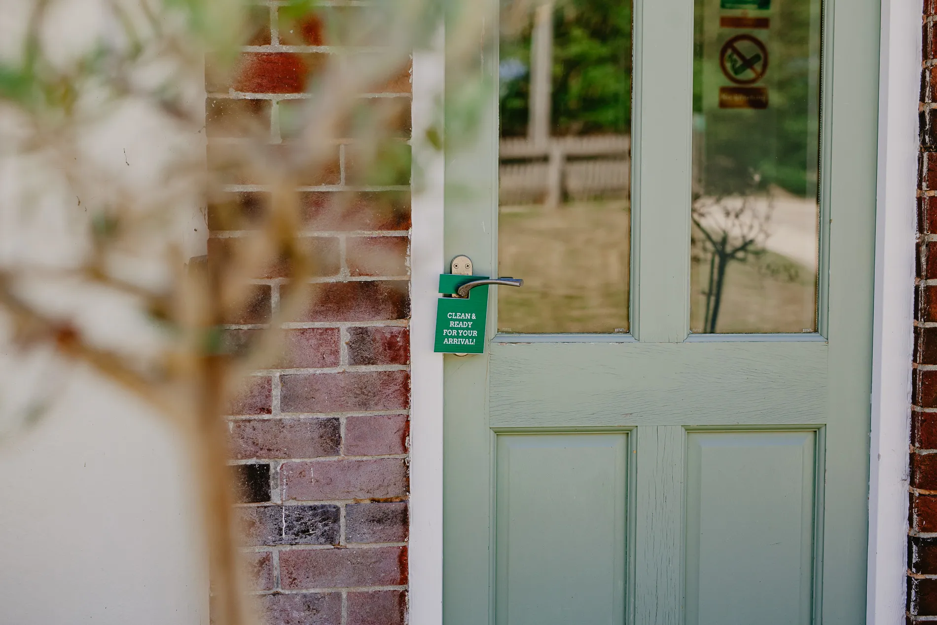 Green cottage door with a ‘clean and ready for your arrival’ tag on the handle at Tapnell Farm