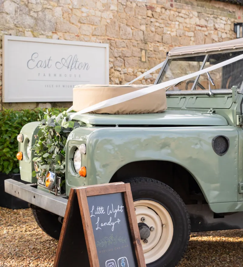 Vintage green Land Rover wedding car display outside East Afton Farmhouse on the Isle of Wight