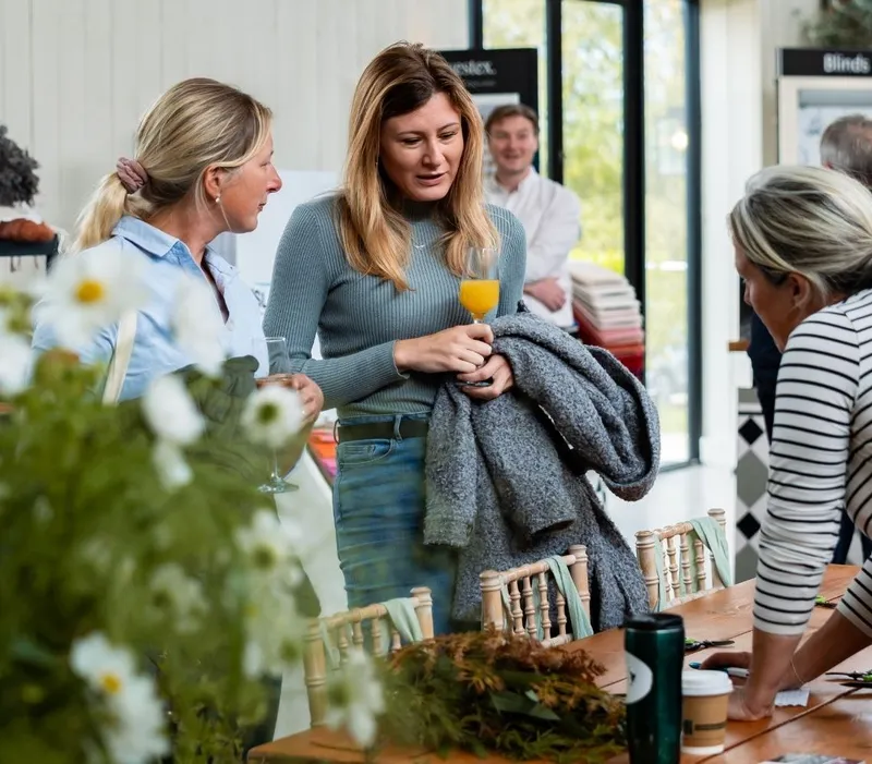 Visitors chatting around a wooden table at an interiors showroom event