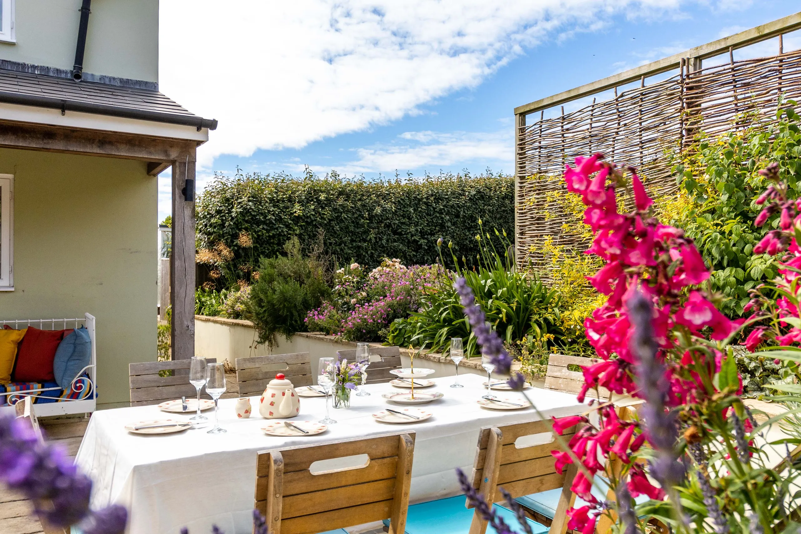 Outdoor dining table set with crockery and glasses on a sunny patio garden at Poachers Lodge
