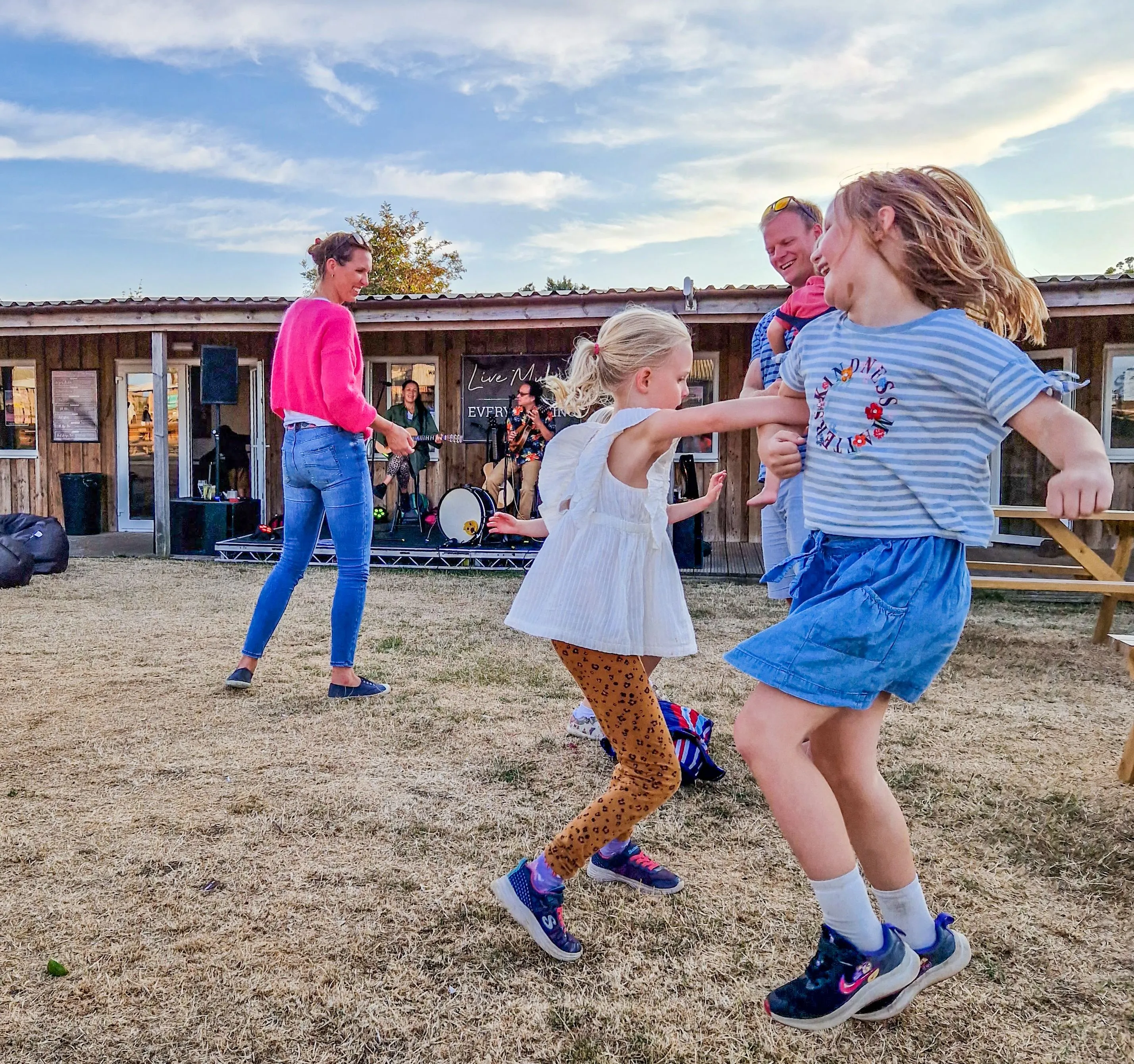 Children and families dancing on the grass in front of a live music performance at Tapnell Farm