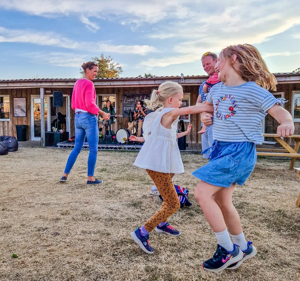 Children and families dancing on the grass in front of a live music performance at Tapnell Farm