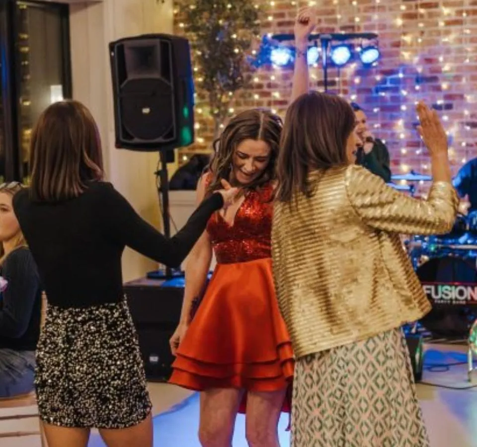Guests dancing at a Christmas party with fairy lights and live music in the background