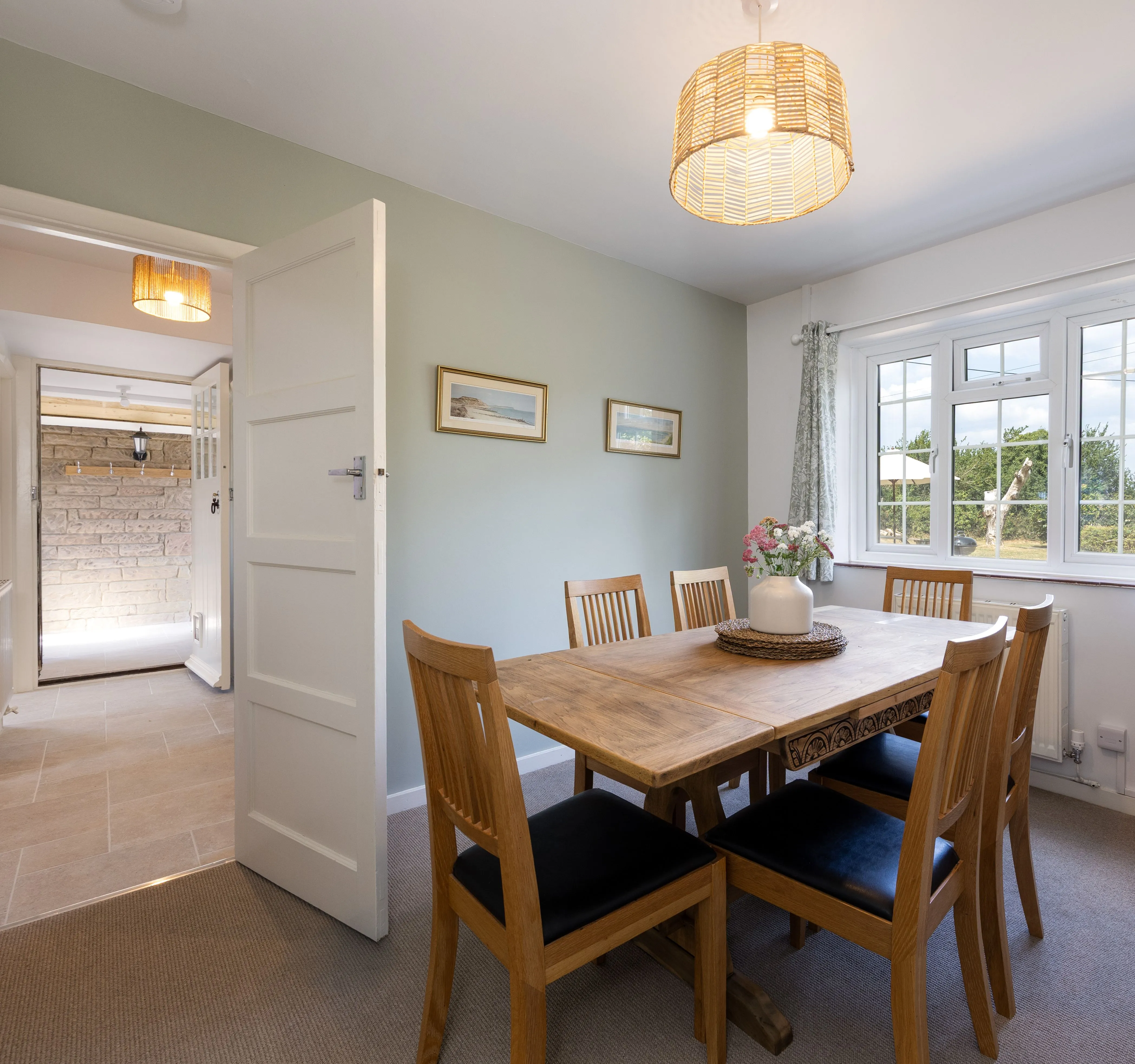 Bright cottage dining room with wooden table, chairs and large window