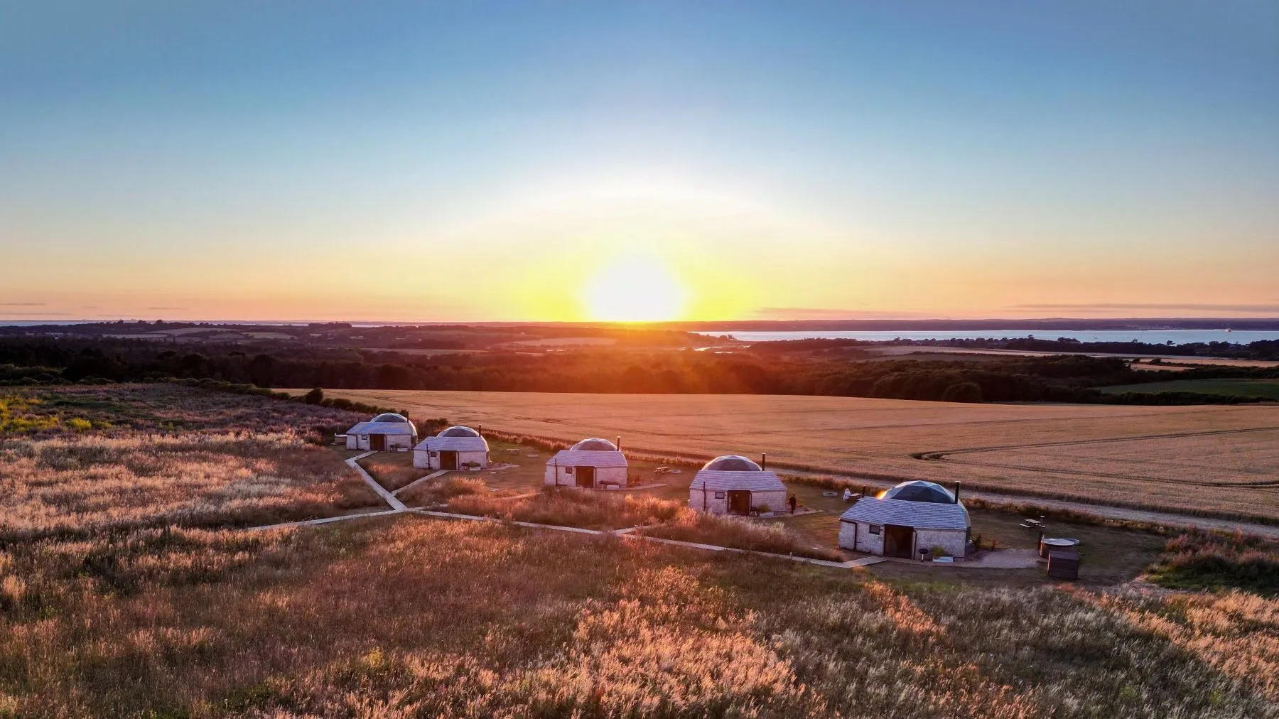 Five white domes in a grassy field at sunset