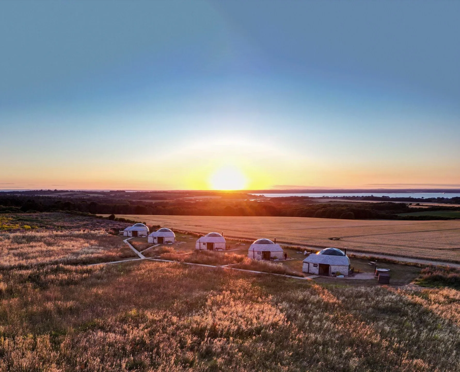 Five white domes in a grassy field at sunset