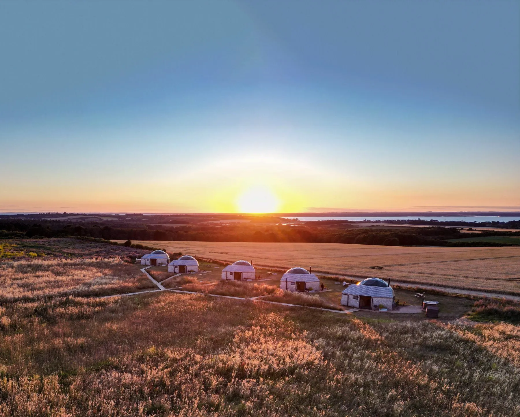 Five white domes in a grassy field at sunset