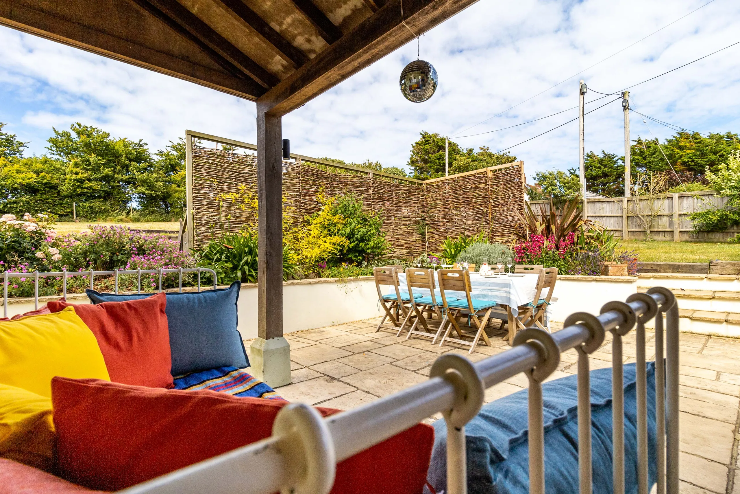 Covered garden patio with outdoor dining table and colourful cushions