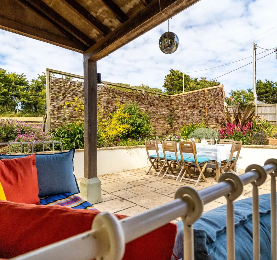 Covered garden patio with outdoor dining table and colourful cushions
