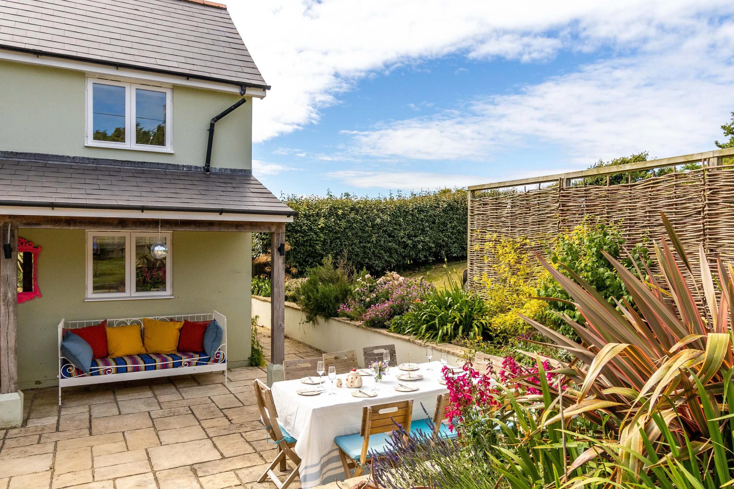 Sunny patio garden at Poachers Lodge with outdoor dining table and colourful bench seating
