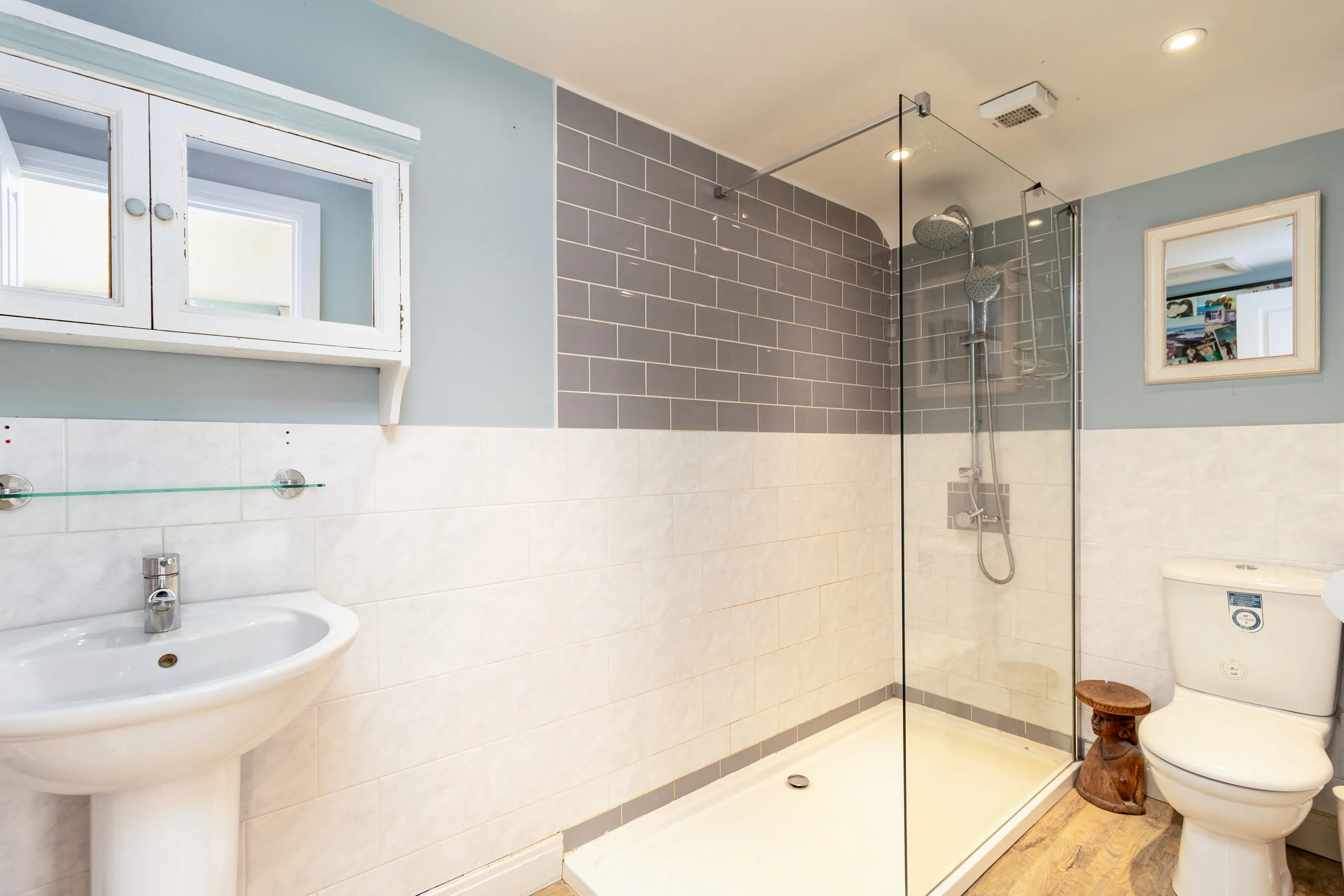 Modern bathroom with walk-in shower, grey and white tiles, pedestal sink and toilet