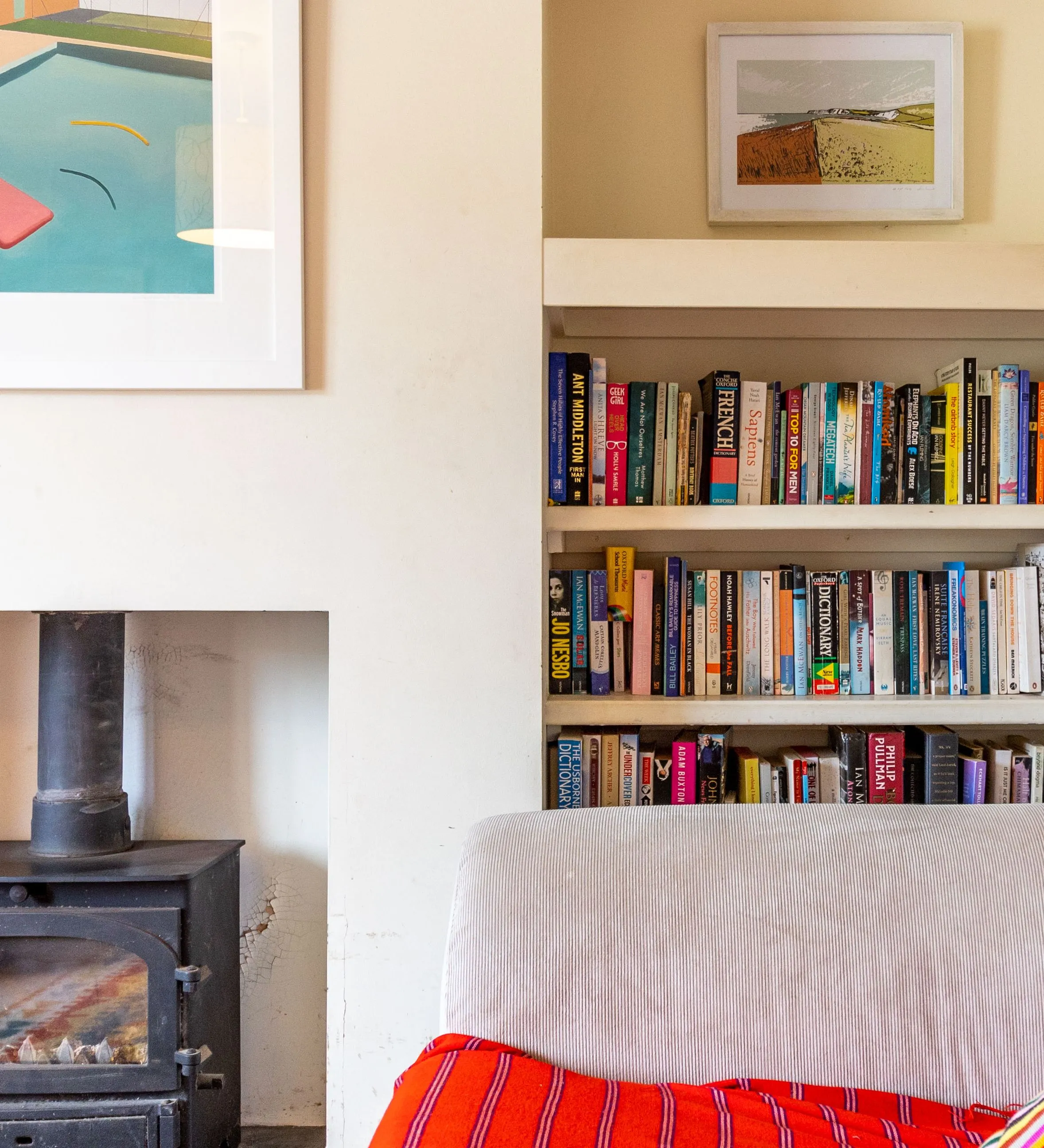 Cosy living room corner with wood-burning stove, built-in bookcase and striped cushion