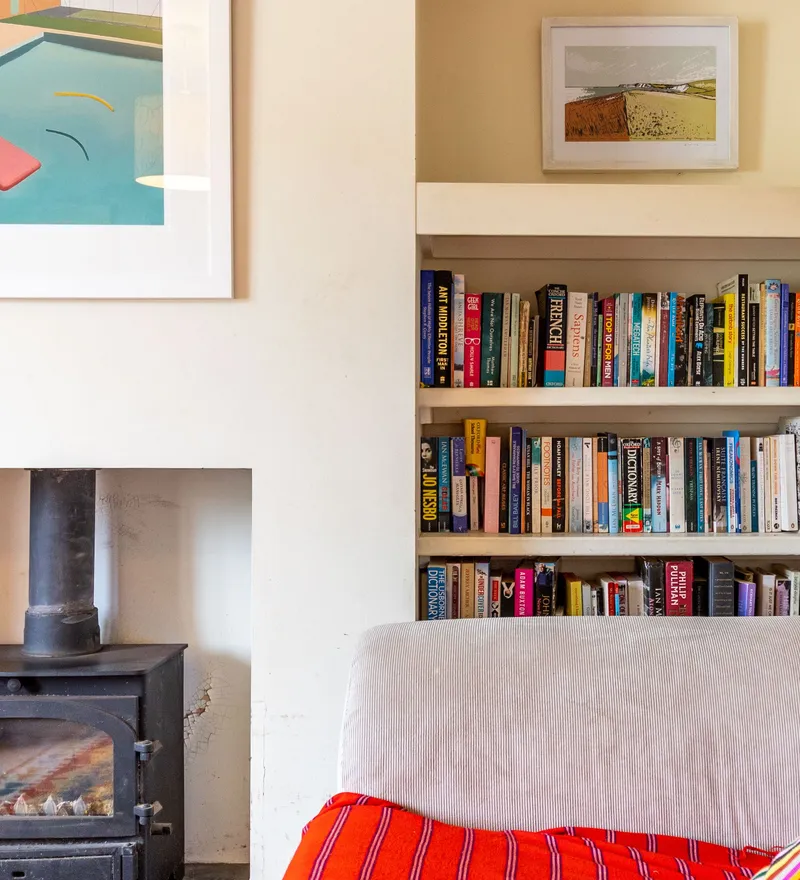 Cosy living room corner with wood-burning stove, built-in bookcase and striped cushion