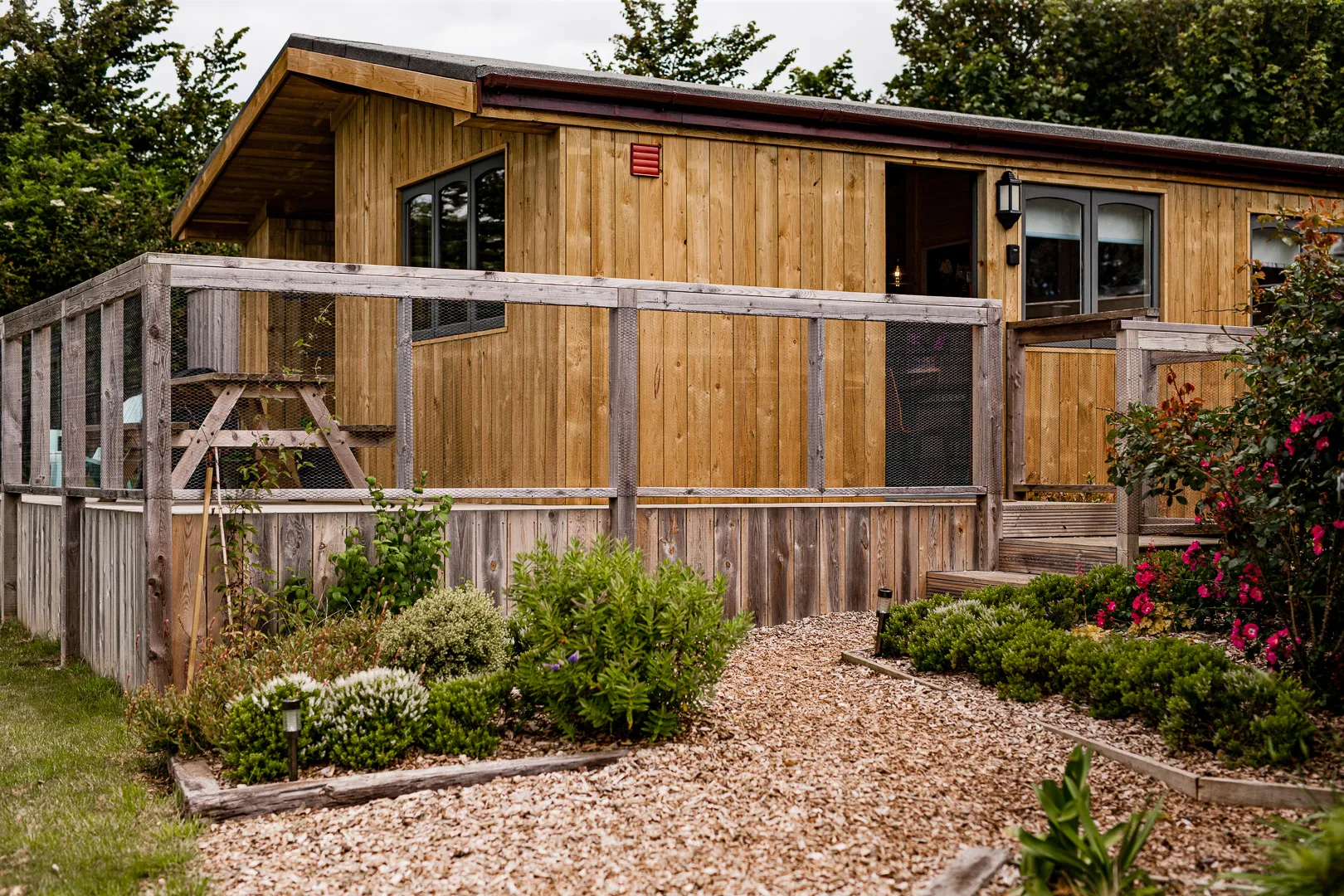 Timber lodge with fenced decking and garden path at Poachers Perch