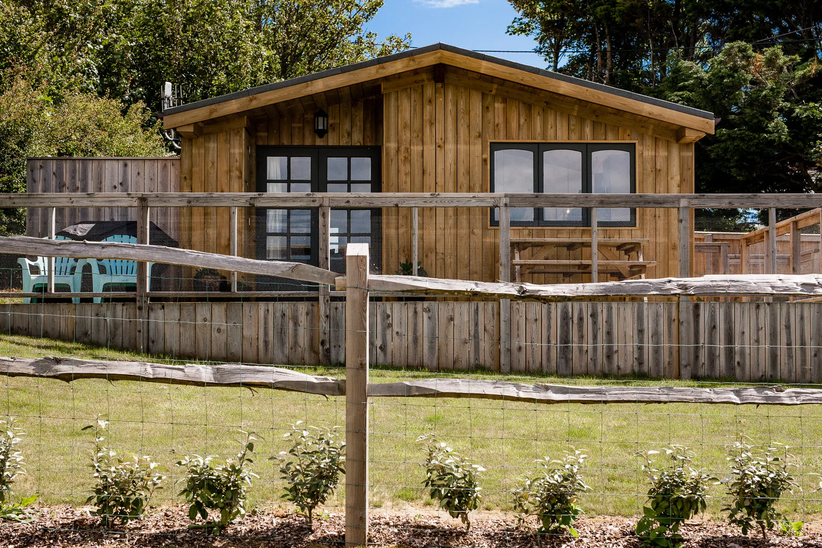 Timber lodge with a fenced veranda and outdoor seating in a leafy garden