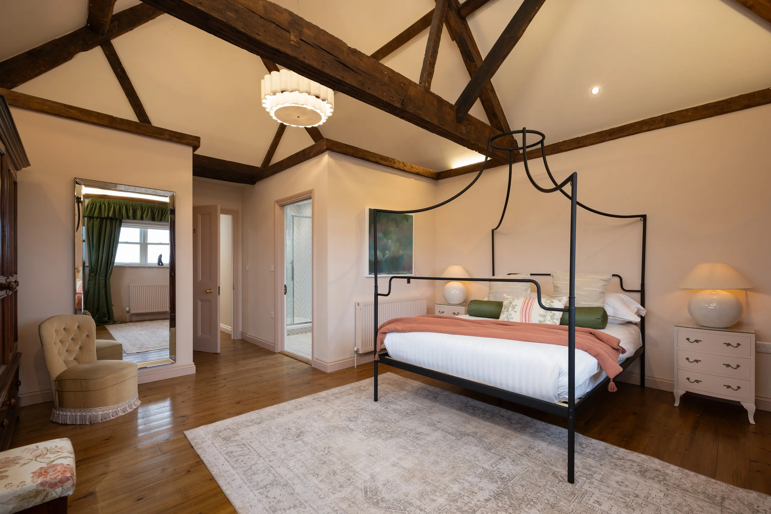 Spacious farmhouse bedroom with exposed wooden beams and a black canopy bed