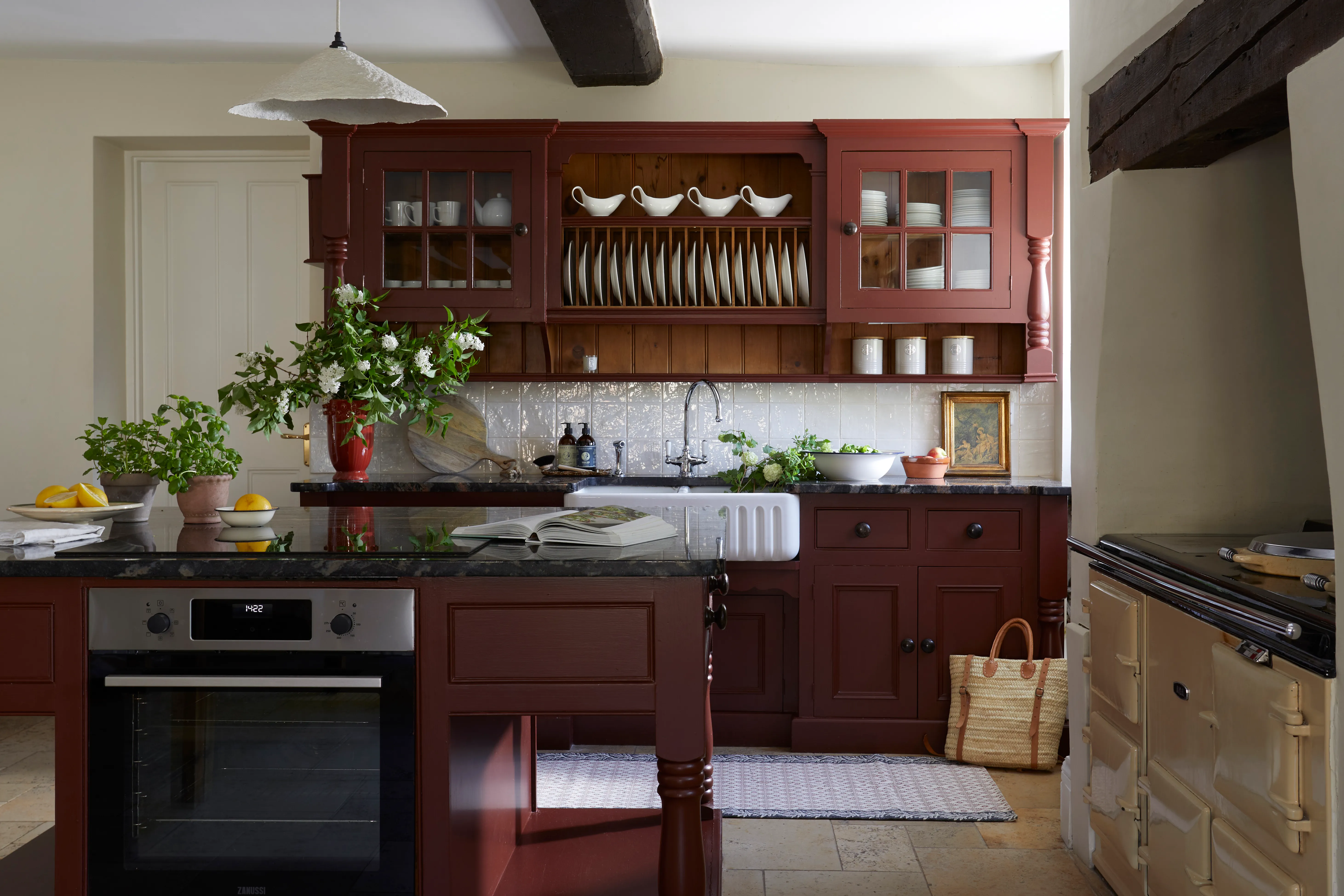 Traditional farmhouse kitchen with burgundy cabinets, black worktops, a Belfast sink and open plate rack
