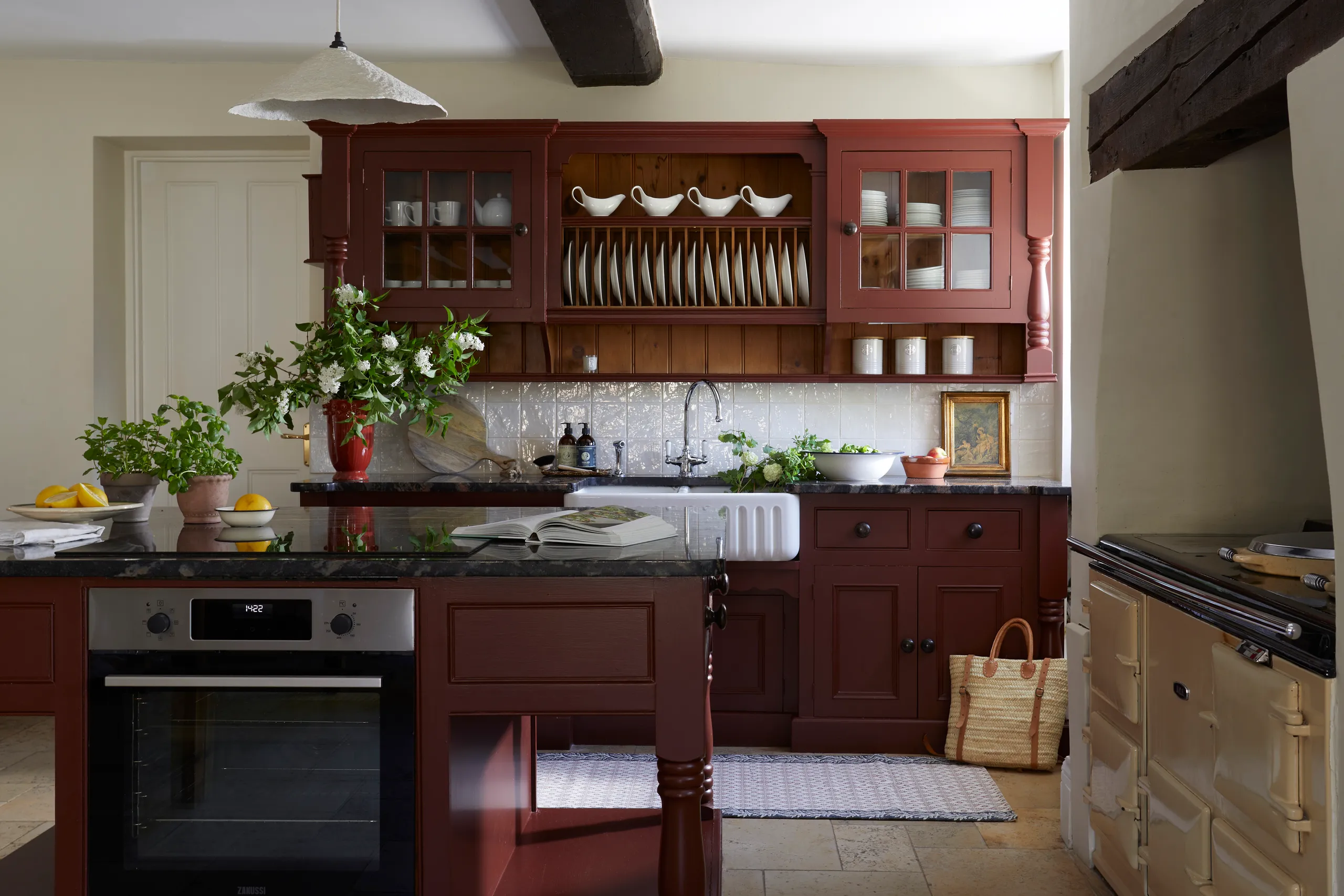 Traditional farmhouse kitchen with burgundy cabinets, black worktops, a Belfast sink and open plate rack