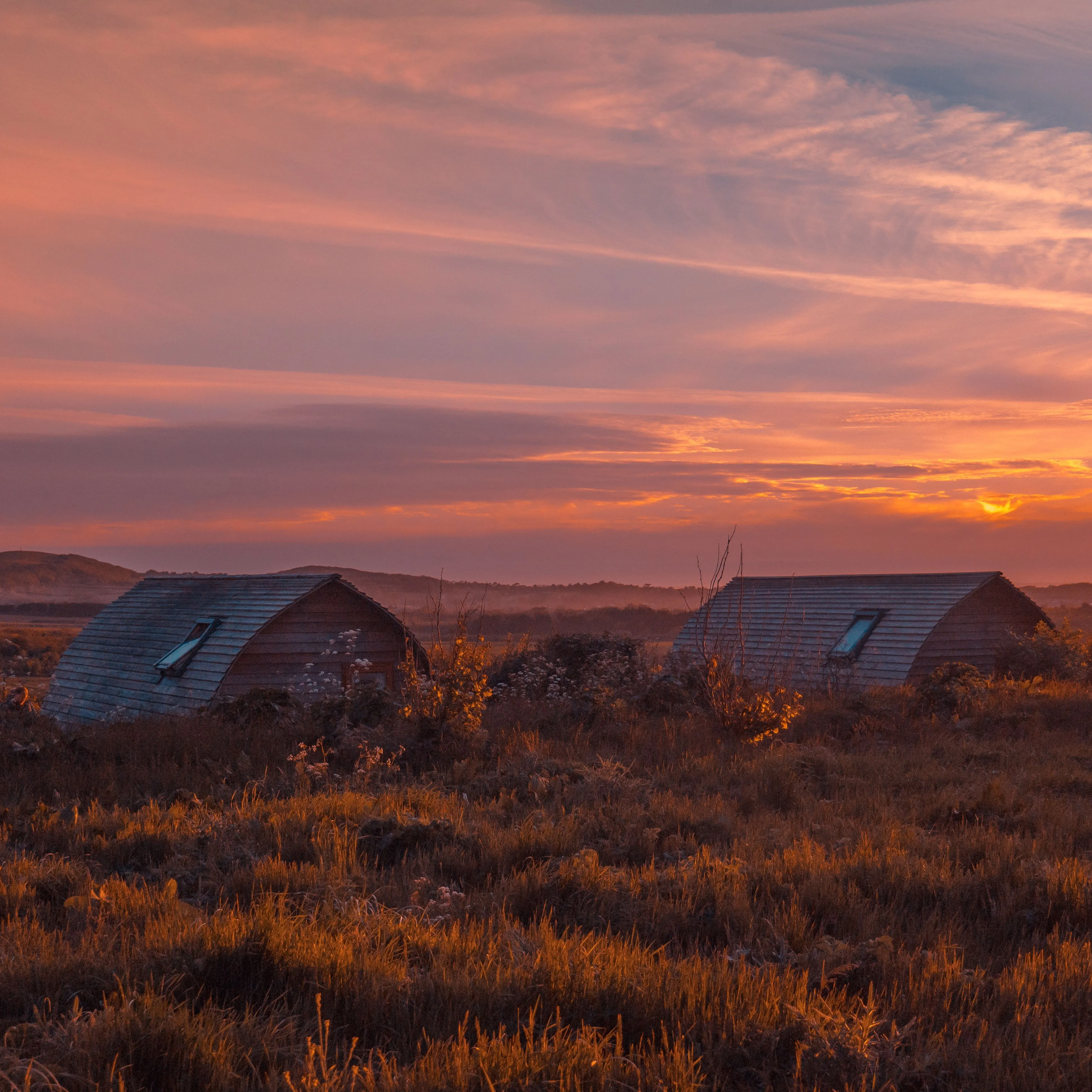 Eco pods at Tapnell Farm with a sunset sky in the background