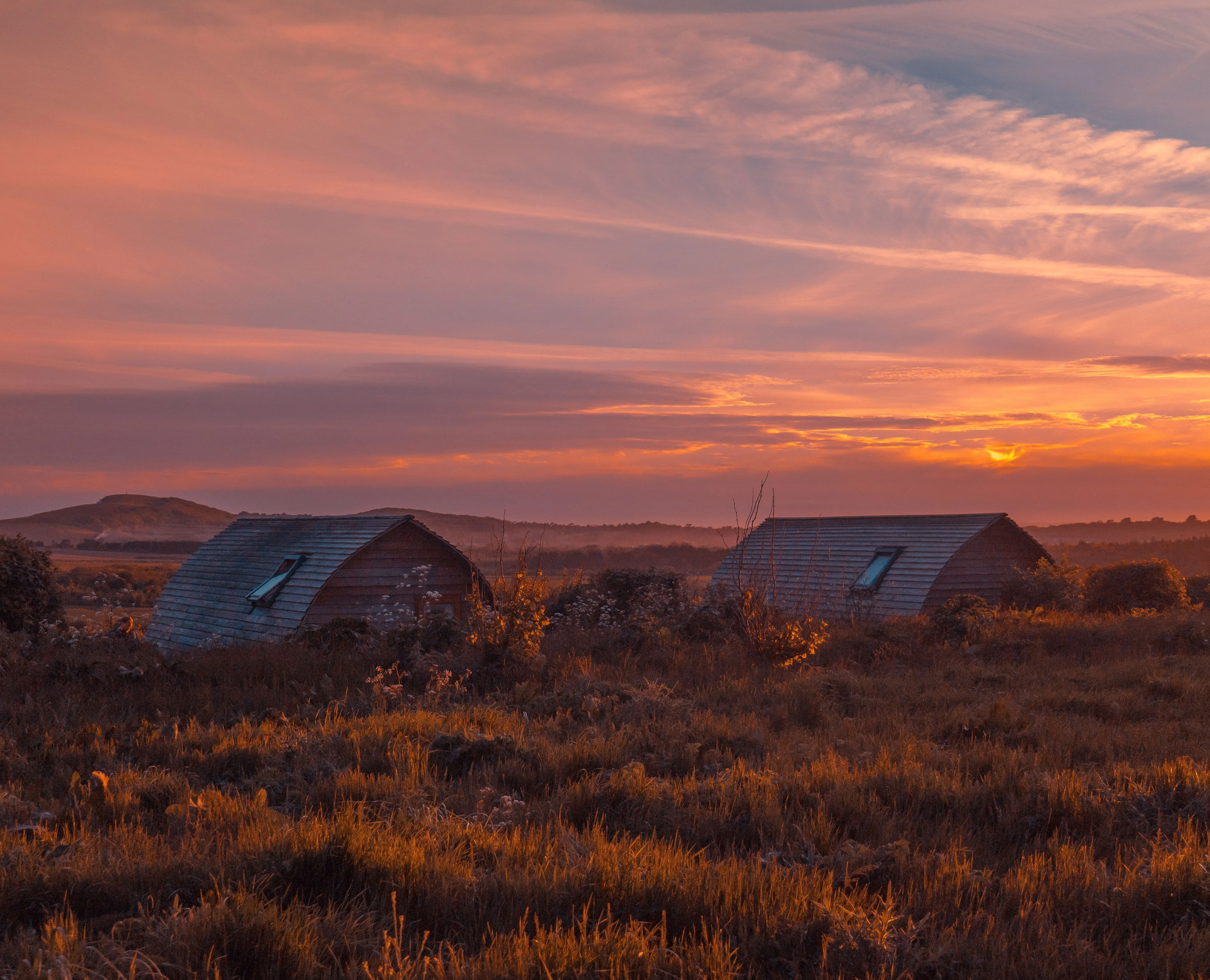 Eco pods at Tapnell Farm with a sunset sky in the background