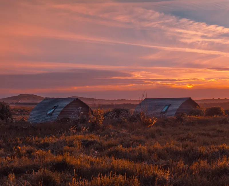 Eco pods at Tapnell Farm with a sunset sky in the background