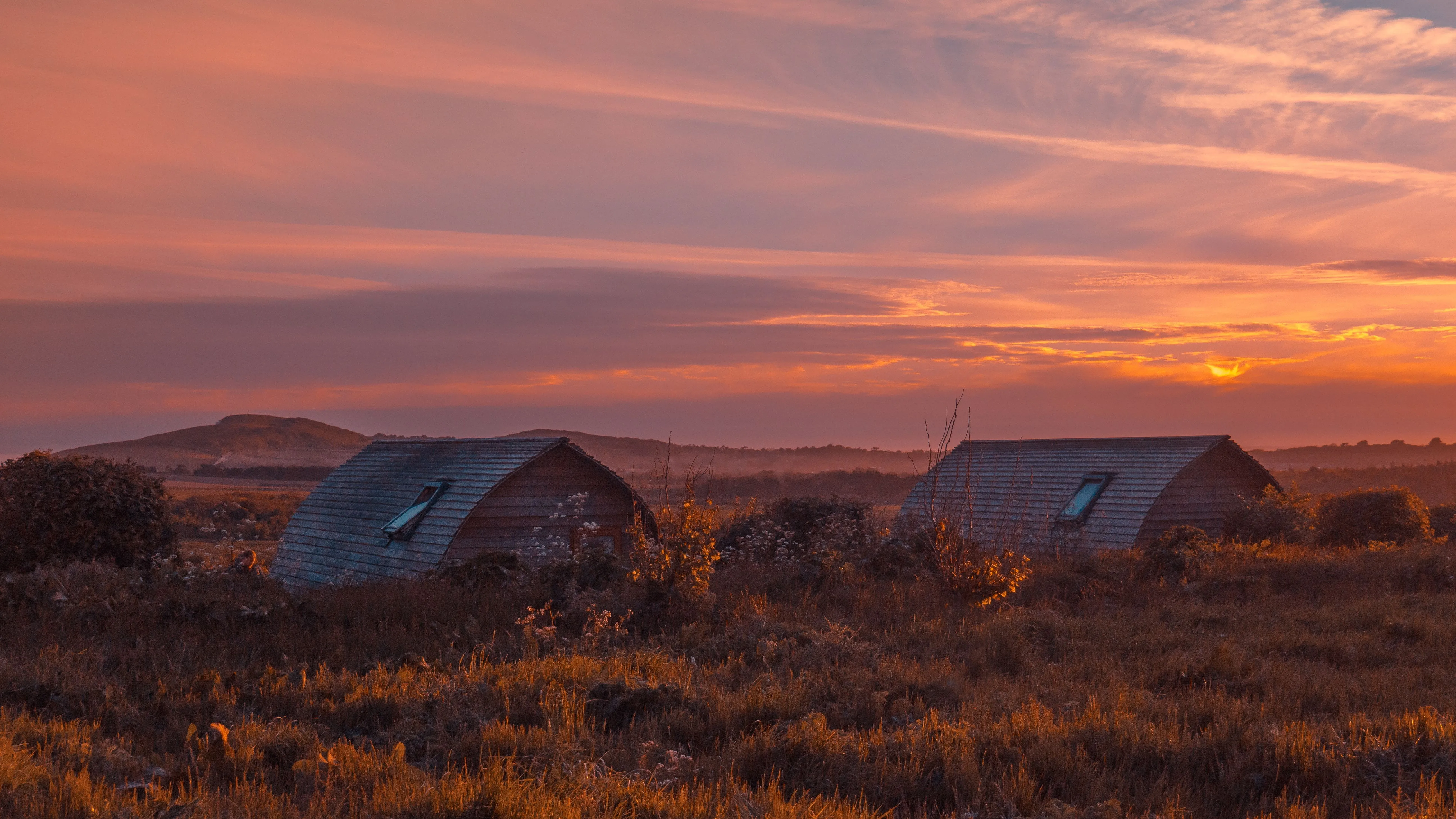 Eco pods at Tapnell Farm with a sunset sky in the background