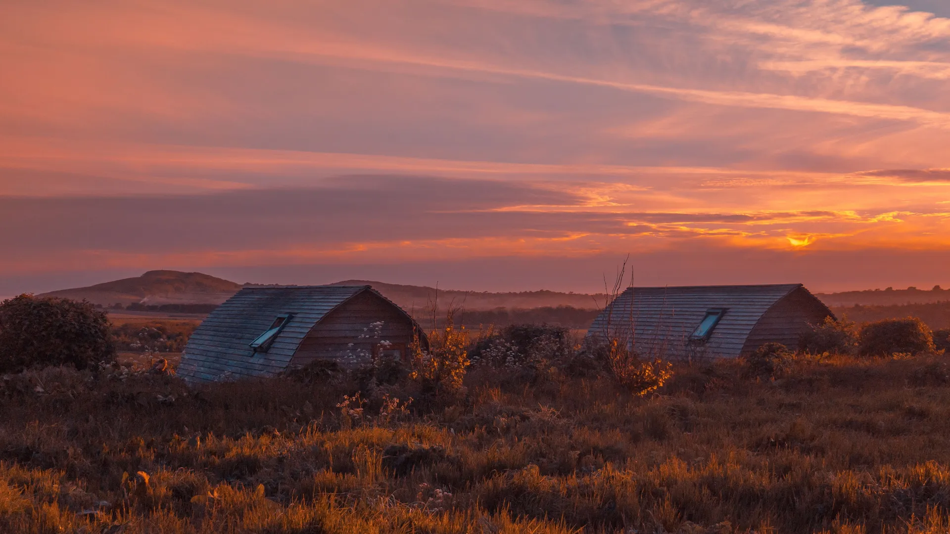 Eco pods at Tapnell Farm with a sunset sky in the background