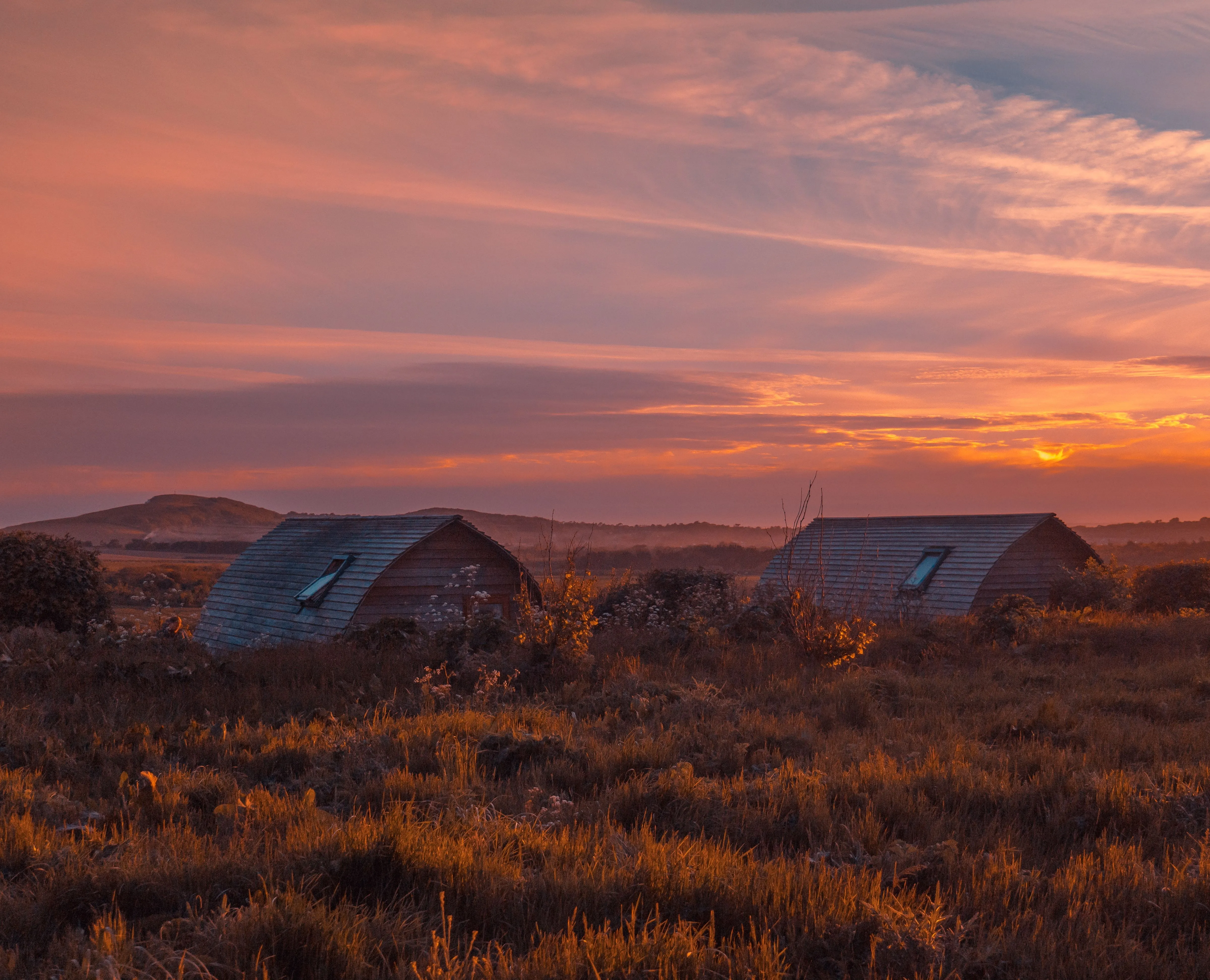Eco pods at Tapnell Farm with a sunset sky in the background