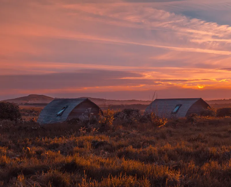 Eco pods at Tapnell Farm with a sunset sky in the background