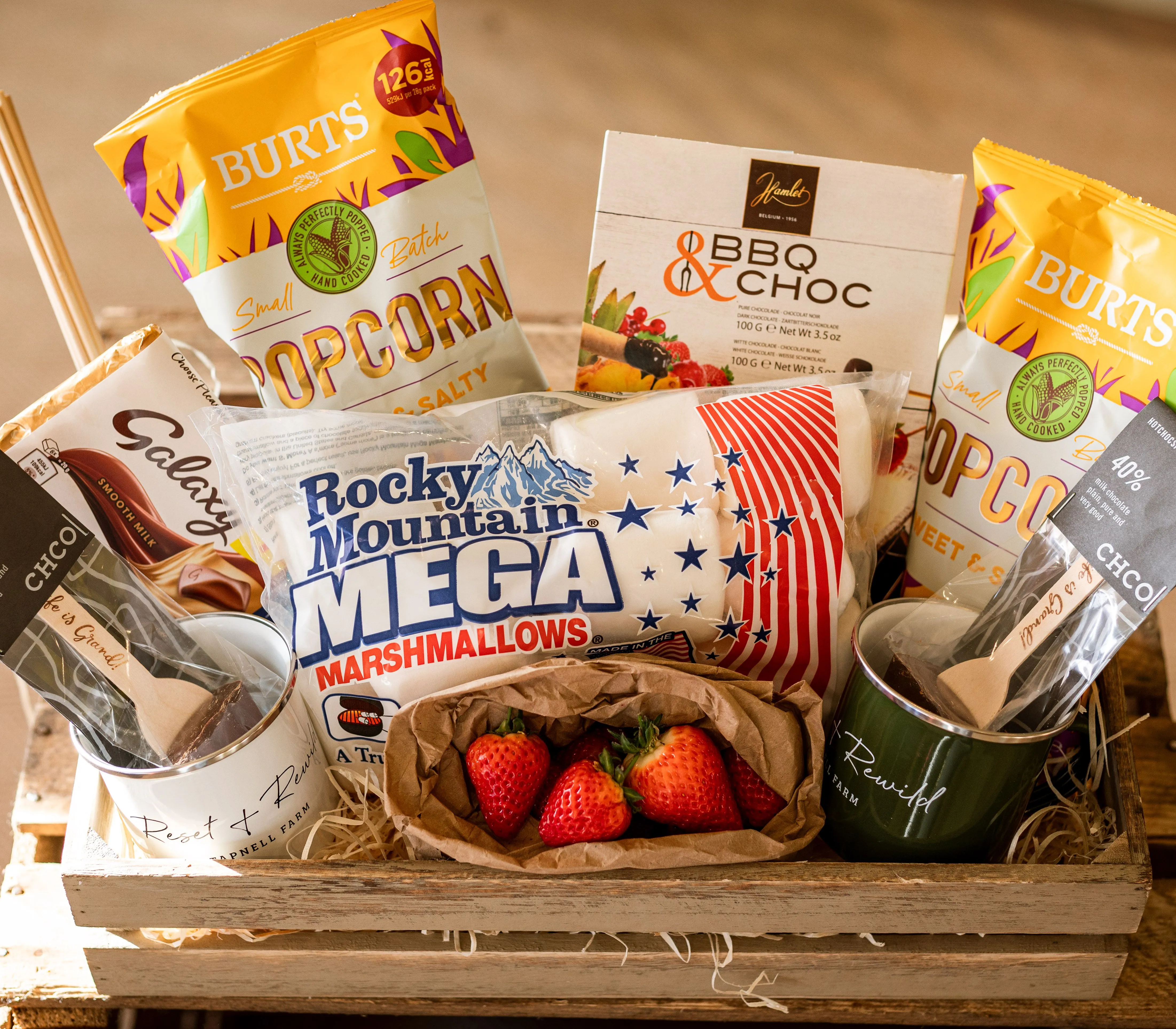 Wooden hamper crate with popcorn, marshmallows, chocolate and strawberries