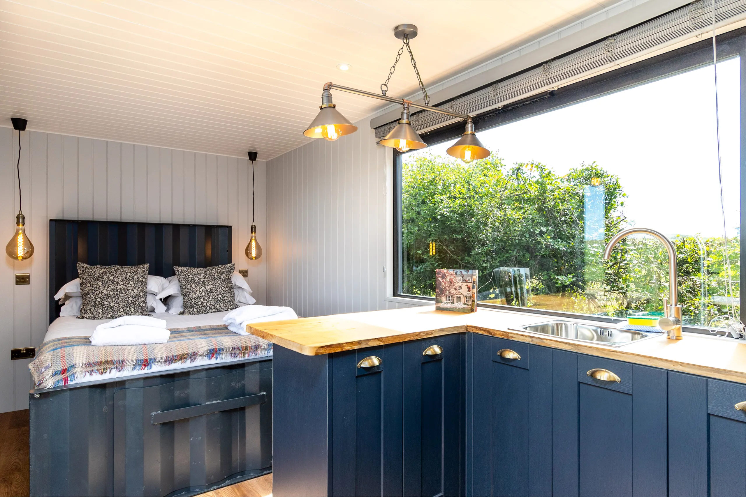Cosy studio room with double bed and compact kitchenette beside a large picture window