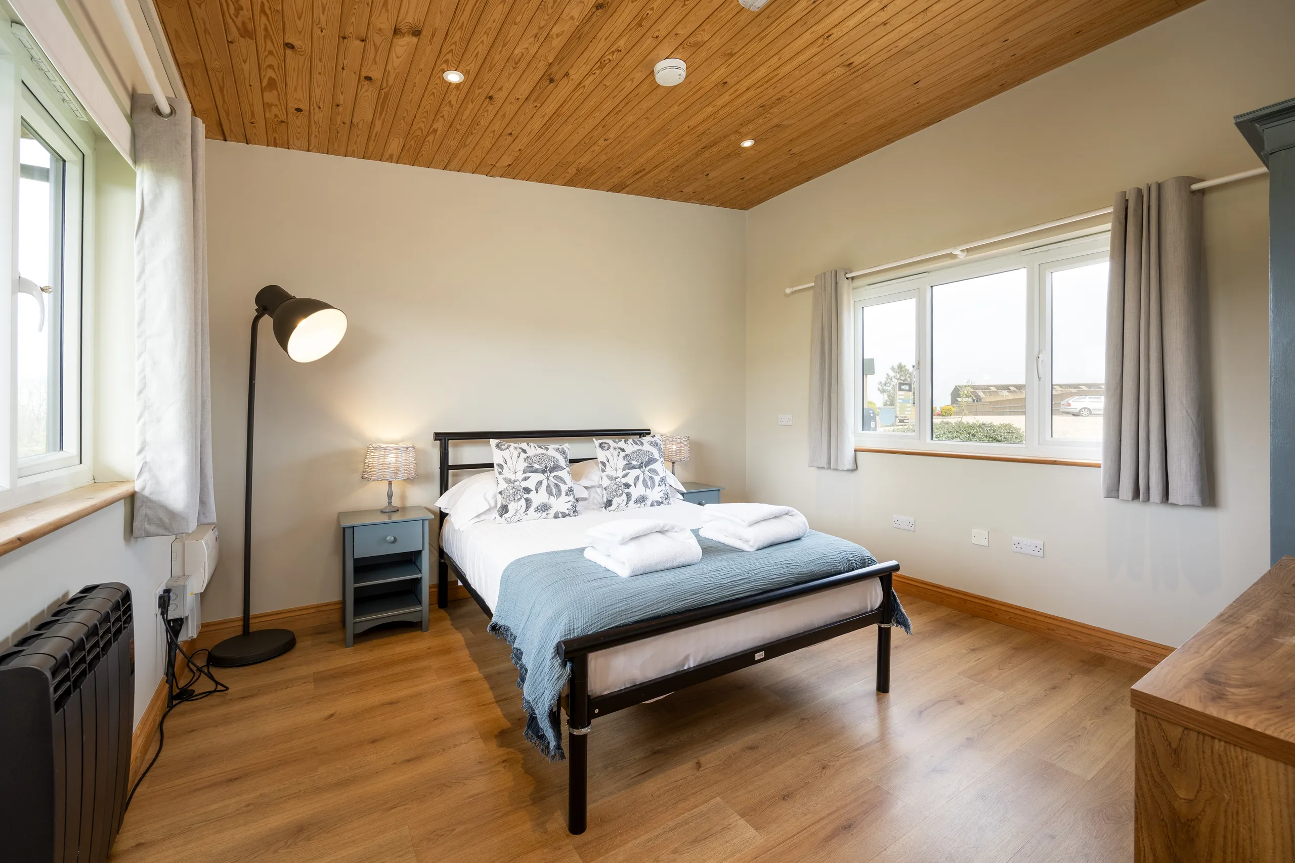 Bedroom at Tapnell Farm The Little Lodge with double bed, blue throw, bedside lamps and windows