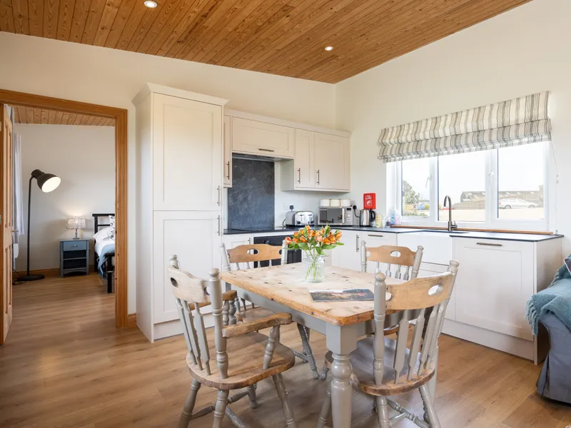 Cosy lodge kitchen-diner with wooden table, white cupboards and large window