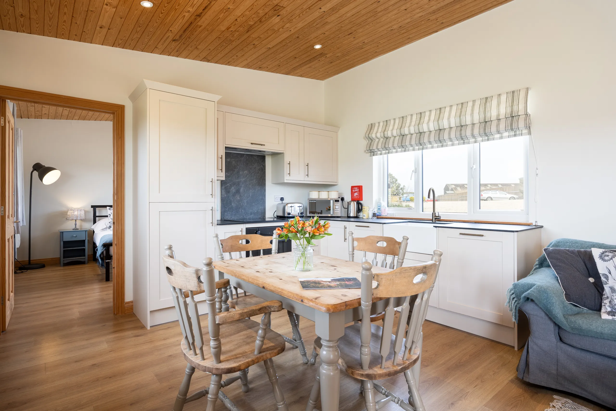 Cosy lodge kitchen-diner with wooden table, white cupboards and large window