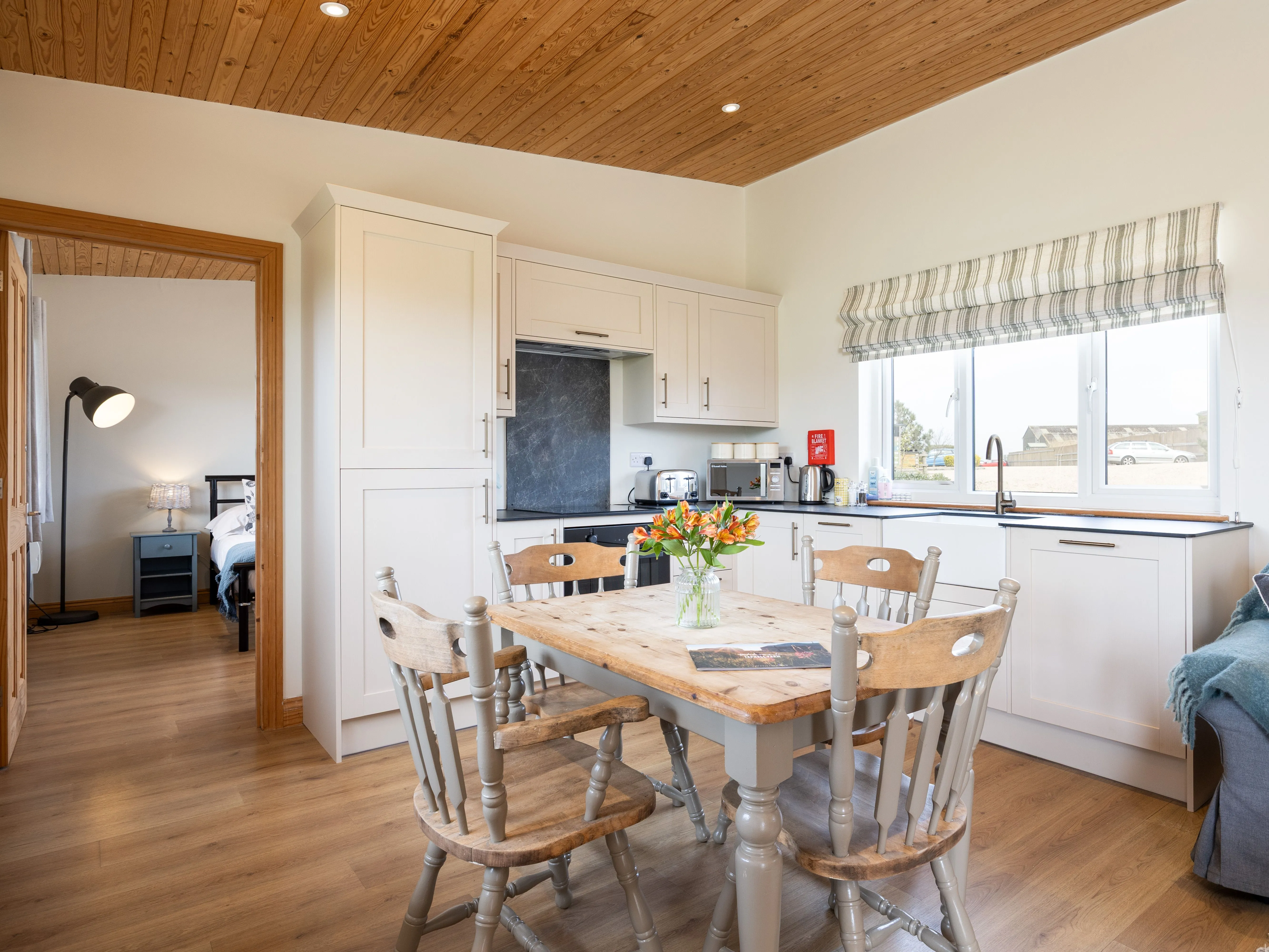 Cosy lodge kitchen-diner with wooden table, white cupboards and large window