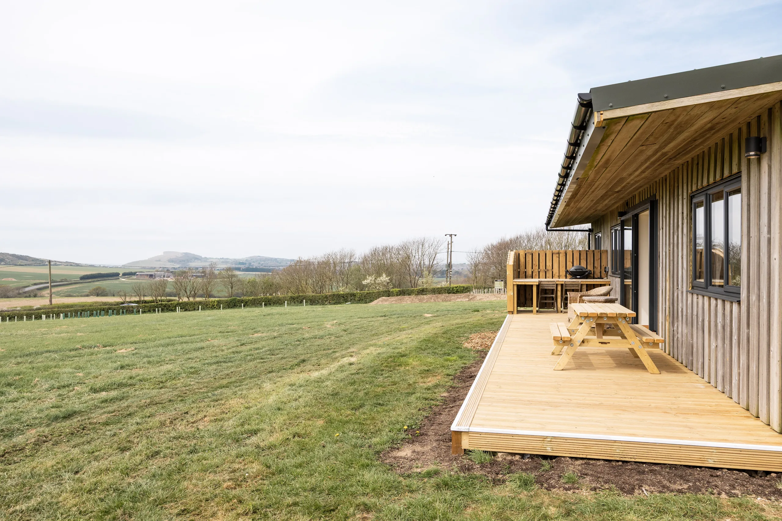 Wooden lodge with decking and picnic table overlooking rolling countryside