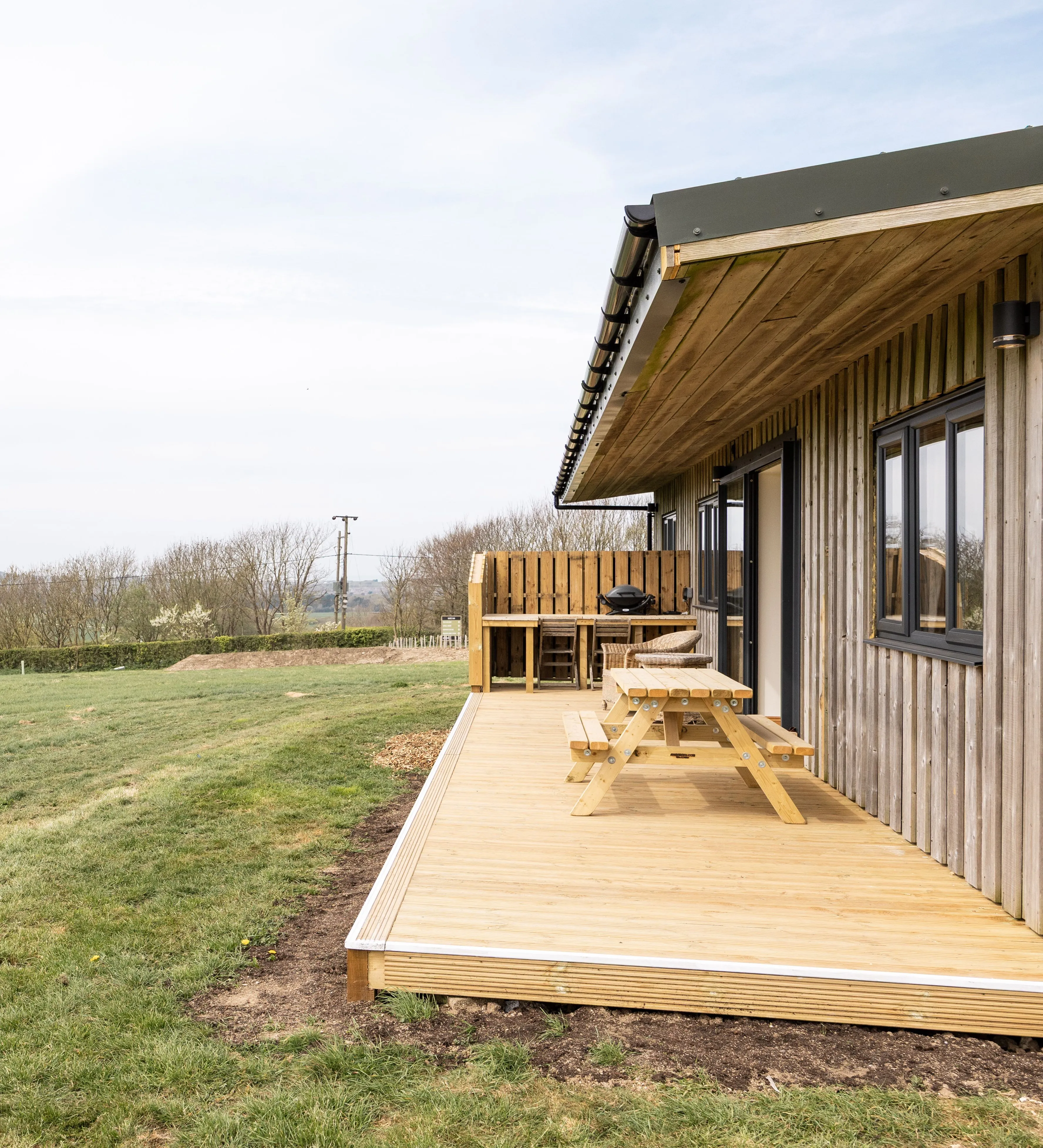 Wooden lodge with decking and picnic table overlooking rolling countryside