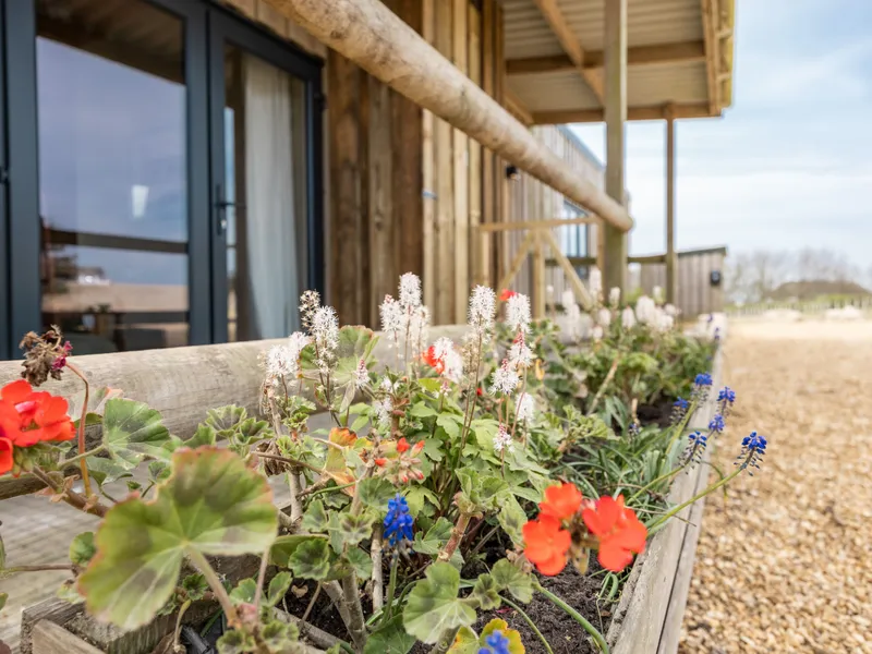 Flower-filled wooden planter beside a timber lodge with glass doors and balcony