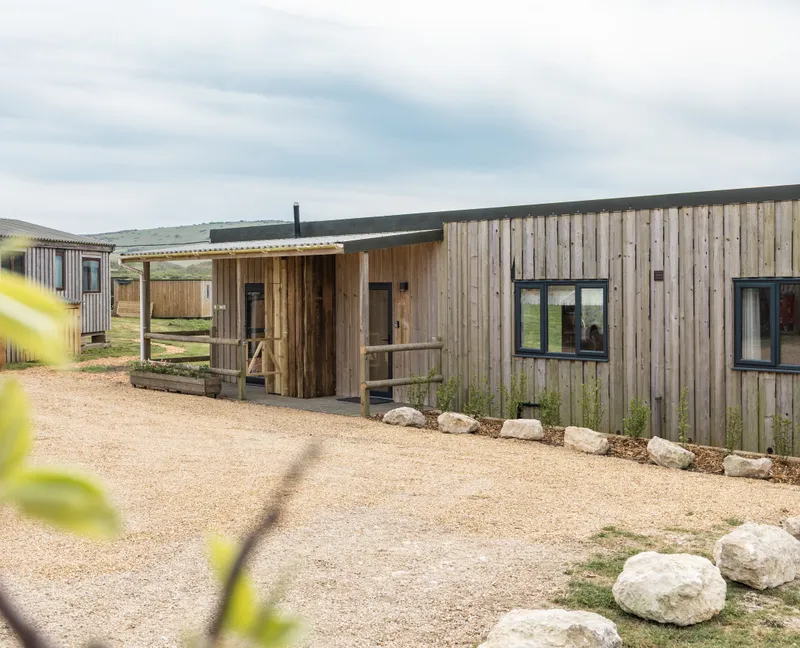 Exterior of a modern timber-clad lodge with gravel driveway and countryside views
